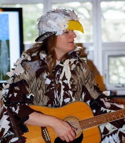 A person from SCARCE entertaining a crowd by strumming a guitar