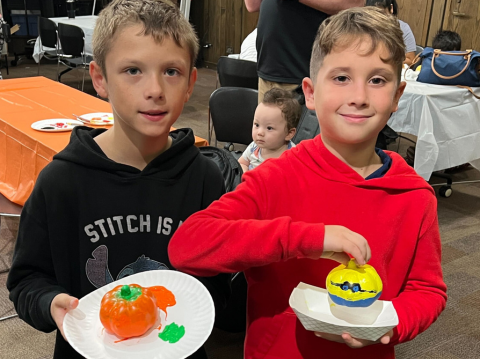 Two boys holding painted pumpkins