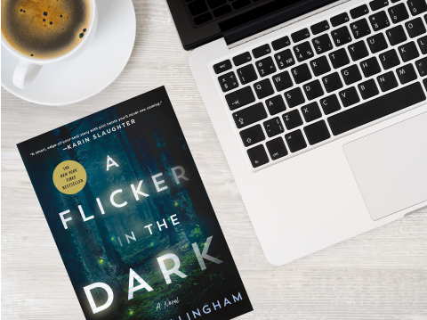 Book "A Flicker in the Dark" next to laptop and coffee